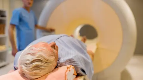 Getty Man with grey hair lying down about to enter an MRI machine.