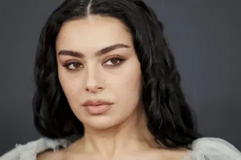 EPA-EFE/REX/Shutterstock A close up shot of Pop star Charli XCX looks smouldering and pouts. She has brown eye shadow and clear skin on a red carpet.