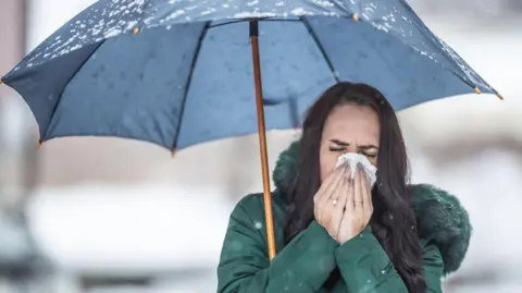 Getty Images Woman with umbrella sneezing